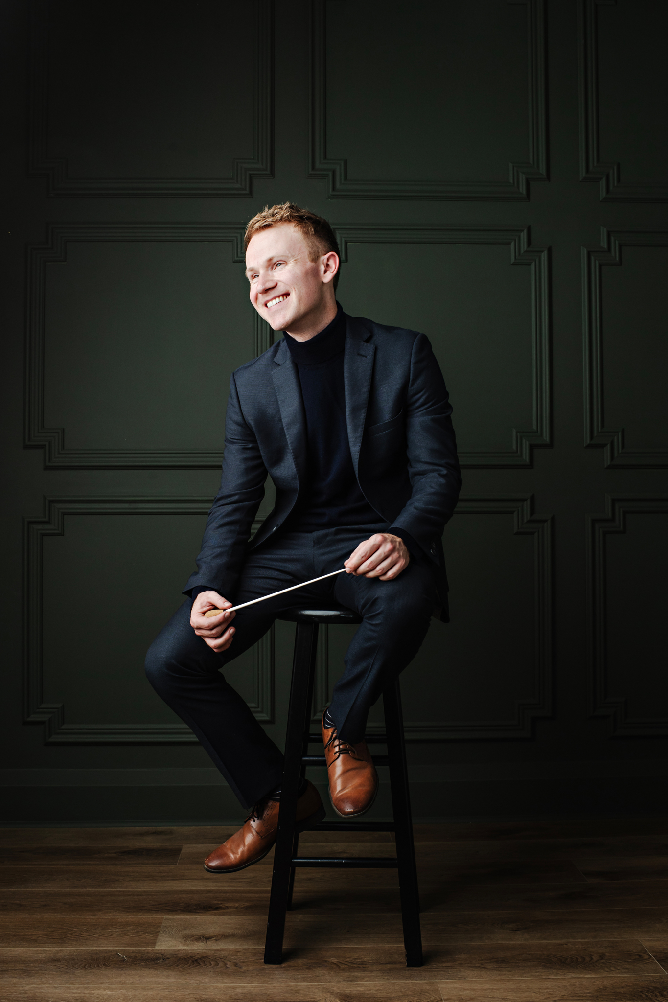 Connor O’Kane seated with a conductor’s baton